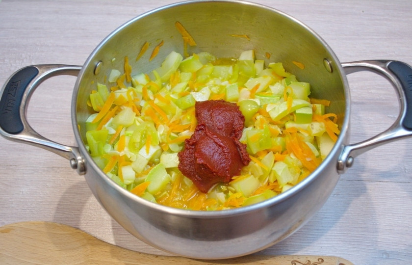 1. Этап. Кабачковая икра без жарки: Добавьте в кастрюлю томатную пасту. Перемешайте. Добавьте соль, сахар, специи по вкусу. Можно подлить еще немного воды (при необходимости).