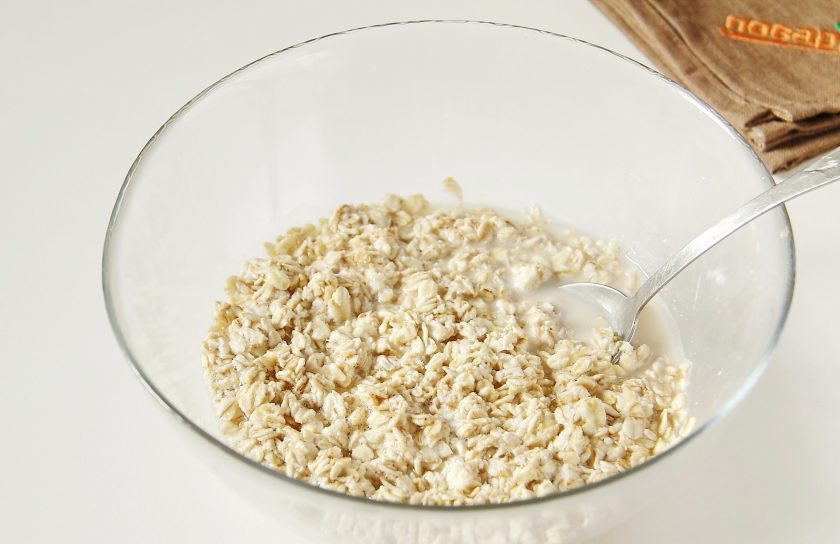 1. Этап. Овсяная запеканка с яблоком: Овсяные хлопья переложите в миску и так же залейте кипятком. Перемешайте и оставьте на 10 минут, чтобы хлопья набухли.