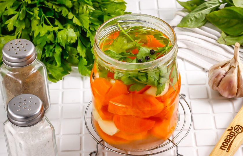 1. Этап. Маринованный чеснок с морковью на зиму: В банку к моркови и чесноку выложите пару веточек петрушки и влейте горячий маринад.
