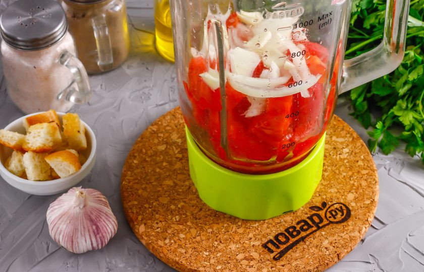 1. Этап. Андалузский суп: Очистите и промойте лук, его половину нарежьте кубиками и добавьте в емкость к томатам. Очистите чесночные зубчики, нарежьте слайсами и добавьте в емкость.