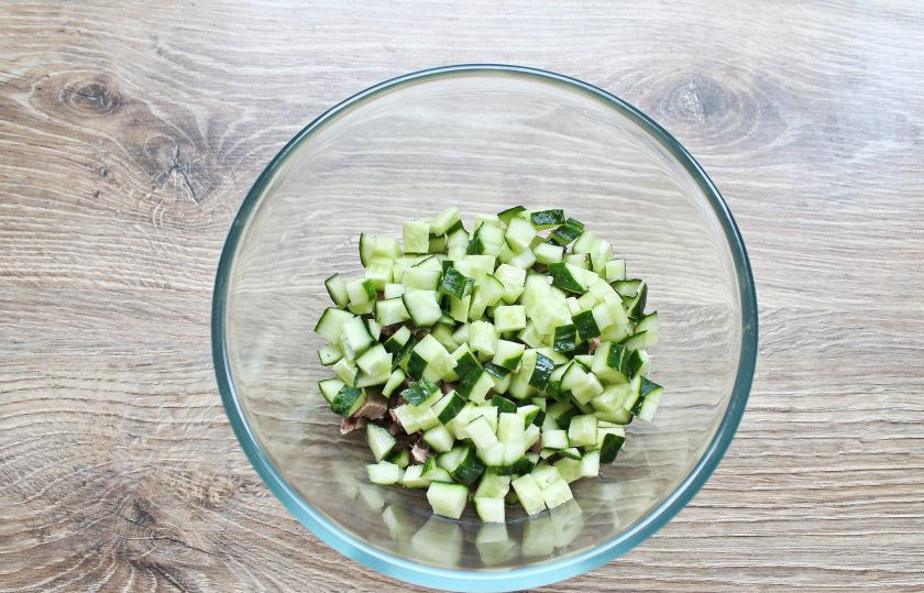 1. Этап. Салат с языком и кедровыми орешками: Свежий огурец порежьте кубиком, точно таким же, как нарезали отварной язык и тоже выложите в миску.