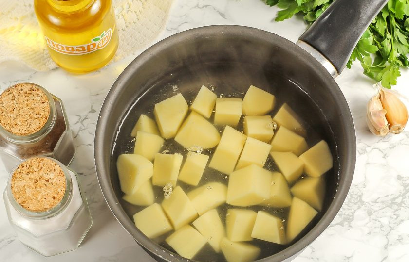 1. Этап. Кукурузный суп с фрикадельками: Картофель нарежьте средними кубиками и высыпьте в кастрюлю, казан или в ковш. Влейте горячую воду и отварите примерно 15 минут, не забыв снять после закипания пену.