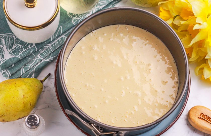 1. Этап. Шарлотка с грушами в аэрогриле: Смажьте форму растительным маслом и влейте в нее приготовленное бисквитное тесто. Если планируете приготовить больше порций, то умножьте норму ингредиентов в несколько раз.