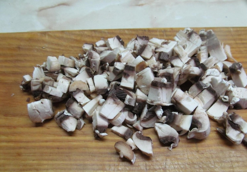 1. Этап. Картошка, фаршированная шампиньонами: Вымойте грибы и лук под холодной водой. Обсушите их с помощью полотенца. С лука снимите верхний слой. Грибы порубите на мелкие кусочки. Лук также порежьте на мелкие кубики или кольца. Разогрейте сковороду.