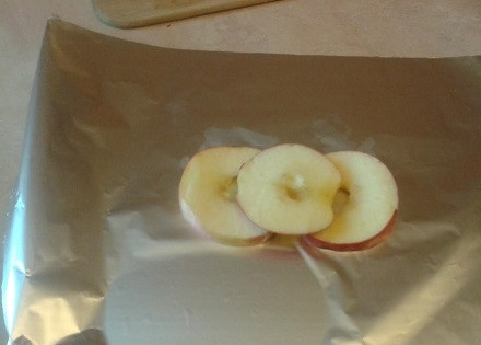 1. Этап. Куриное филе с яблоками и черносливом: Отрываем лист фольги и по центру на него выложим 2-3 яблочных кольца.