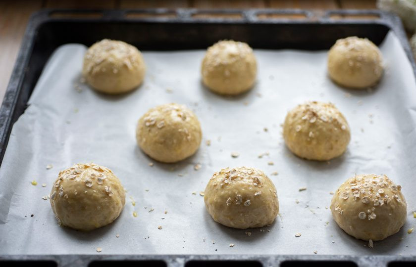 1. Этап. Булочки с овсяными хлопьями: После чего из созревшего теста сформируйте заготовки булочек — отделяйте от общей массы небольшие части весом по 80 грамм и скатывайте из них шарики. Все шарики-заготовки выложите на противень, застеленный пергаментом для выпекания. Каждую будущую булочку смажьте взболтанным яйцом и чуть обсыпьте овсяными хлопьями. Оставьте противень с булочками в покое на 15 минут, а затем отправьте выпекаться в уже разогретую до 180 градусов духовку на 20-25 минут.