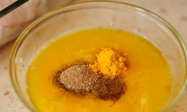 1. Этап. Рецепт курицы с апельсинами в духовке: В небольшую пиалку влейте апельсиновый фреш, добавьте к нему жидкий мед, оливковое масло, кориандр, куркуму и тмин. Затем очистите и натрите на терке зубчики чеснока. Добавьте их в пиалку к остальным ингредиентам и тщательно перемешайте.