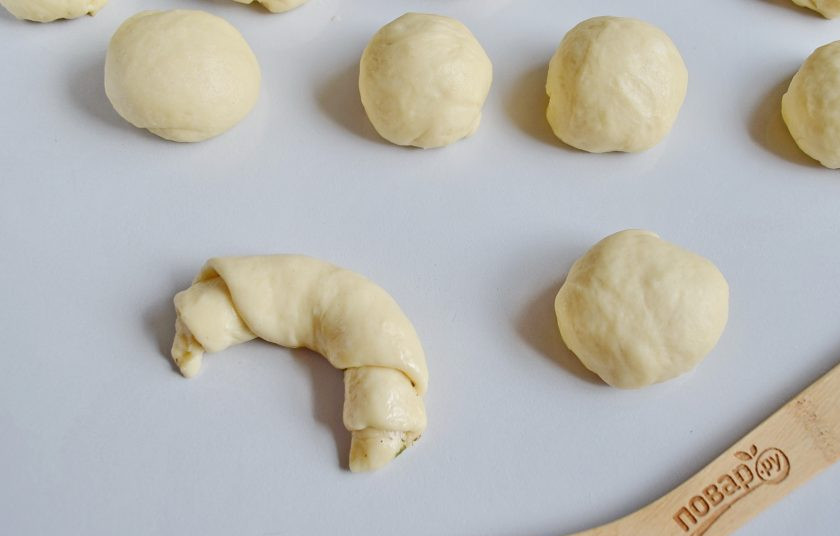 1. Этап. Круассаны-рогалики с прованскими травами: Закрутите рогалик. Это легко сделать так: двумя руками возьмитесь за разрезанные концы, потяните в разные стороны немного и начните сворачивать круассан. После просто изогните его, придавая нужную форму. Такая формовка позволит ему хорошо держать форму.