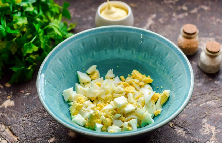 1. Этап. Тарталетки с икрой минтая: Куриные яйца почистите и нарежьте небольшими кубиками, переложите в салатник.