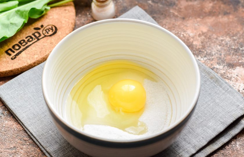 1. Этап. Пирог с яблоками и щавелем: Всыпьте в миску сахар, добавьте куриное яйцо.