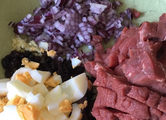 1. Этап. Рецепт кукурузного пирога: 1. Яйца отварите вкрутую, остудите, очистите и нарежьте кубиками. Измельчите говядину, чеснок, красный лук и маслины. На сковороде разогрейте масло и выложите лук с мясом и томатным пюре. Жарьте на среднем огне минут 5.