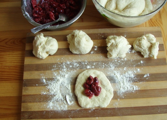 1. Этап. Булочки с вишней: 3. Готовое тесто выложите на присыпанную мукой поверхность и разделите на небольшие шарики. Каждый из них раскатайте и выложите в центр начинку.