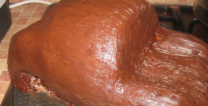 1. Этап. Торт на день рождения мальчику: Пока делаем ганаш, отправляем торт обратно в духовку. Ганаш: в 150 мл жирных сливок на маленьком огне растворяем 150 г черного шоколада. Когда ганаш остынет, обмазываем им торт кулинарной кисточкой.