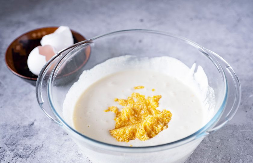 1. Этап. Творожная запеканка с кукурузной крупой: Кукурузную крупу промойте в холодной воде и добавьте в миску к творожной смеси. Перемешайте.