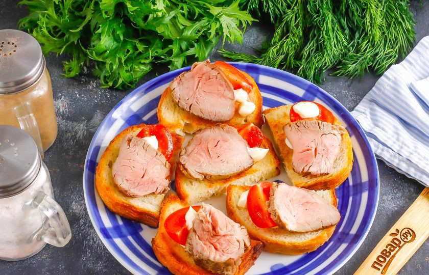 1. Этап. Канапе с ростбифом: Нарежьте ростбиф тонкими ломтиками. Помидоры черри разрежьте пополам. Выложите на хлебную основу.