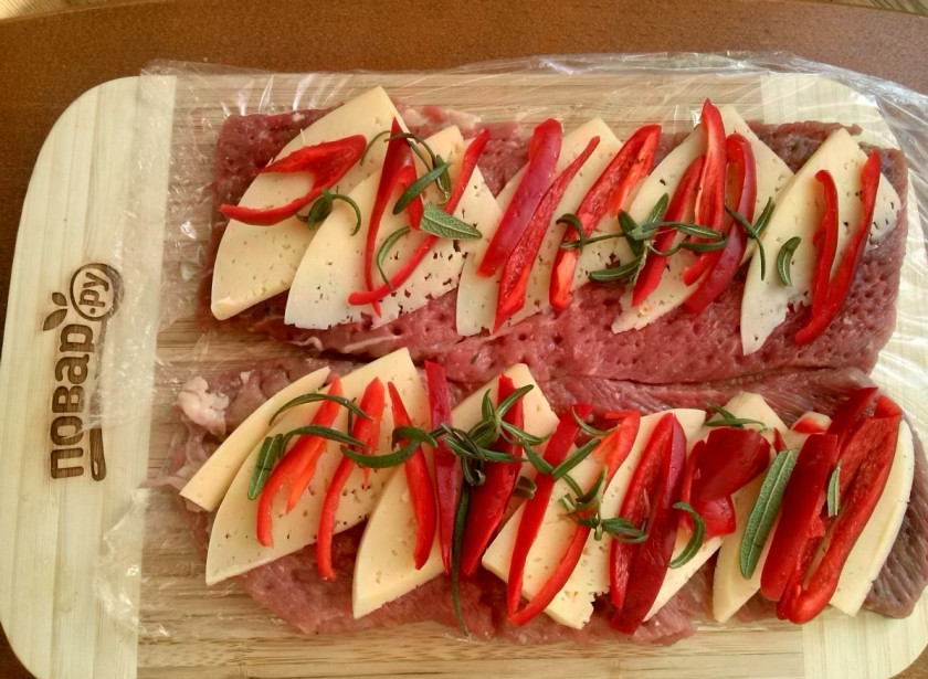 1. Этап. Новогодний рулет из говядины: Выложите начинку поверх мясных пластов, сверните рулеты и закрепите их силиконовыми завязками или кулинарной нитью.