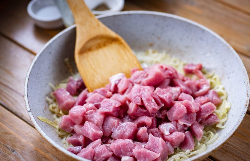 1. Этап. Баклажаны тушеные с картошкой и мясом: К луку выложите кусочки свинины, увеличьте огонь до максимума и обжарьте мясо до легкой золотистой корочки, постоянно помешивая лопаткой.