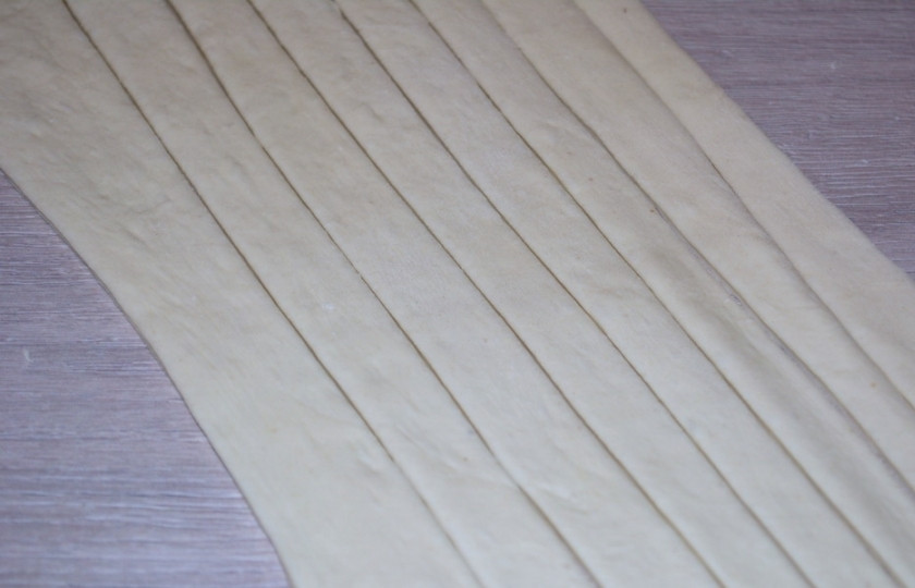 1. Этап. Сосиски в слоеном дрожжевом тесте: Используя нож для пиццы, нарежьте тесто на полоски.