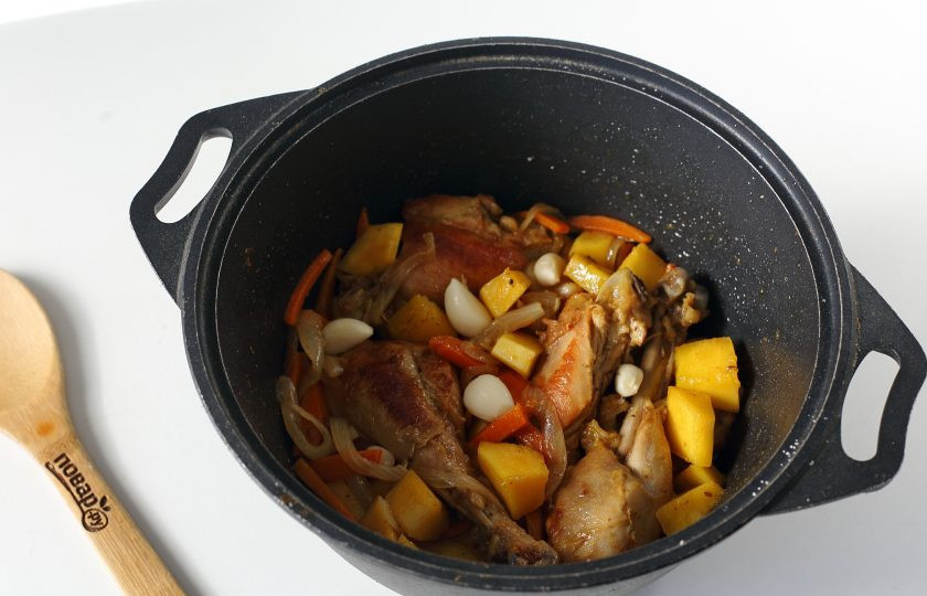 1. Этап. Рис с курицей и тыквой: Добавьте нарезанную крупными кубиками тыкву, прогрейте мясо с овощами пару минут и разложите сверху очищенные зубчики чеснока.