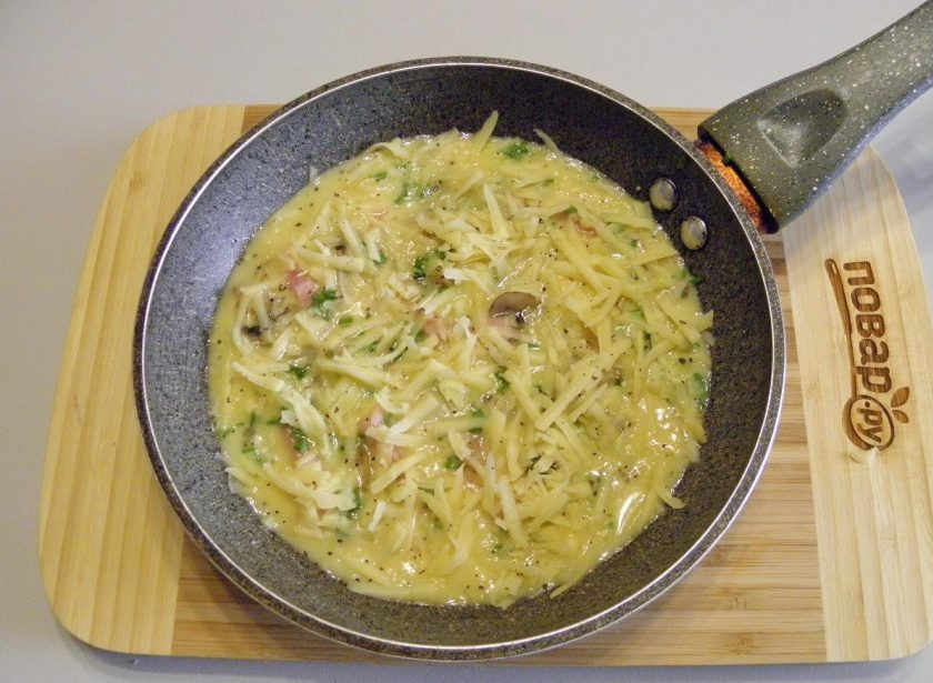 1. Этап. Омлет с ветчиной, грибами и сыром: 6. Добавьте мелко порезанный лук-шиит, тертый сыр. Поместите сковороду на медленный огонь, накройте плотно крышкой и засеките 3-4 минуты.