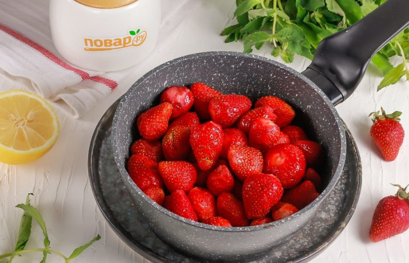 1. Этап. Целая клубника с сахаром на зиму: Оборвите у ягод клубники хвостики, промойте и добавьте их в емкость.