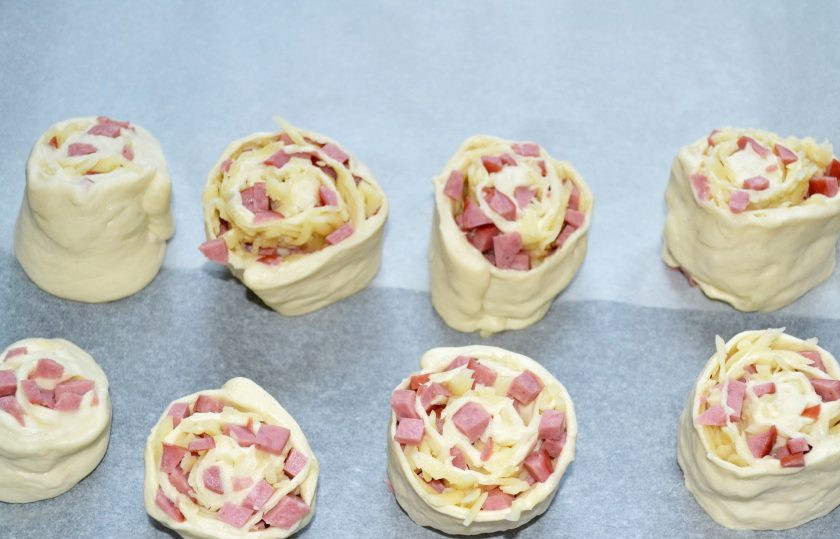 1. Этап. Булочки с колбасой и сыром в духовке: Нарежьте небольшими кусочками и выложите на противень, застеленный пергаментом, срезом вверх.