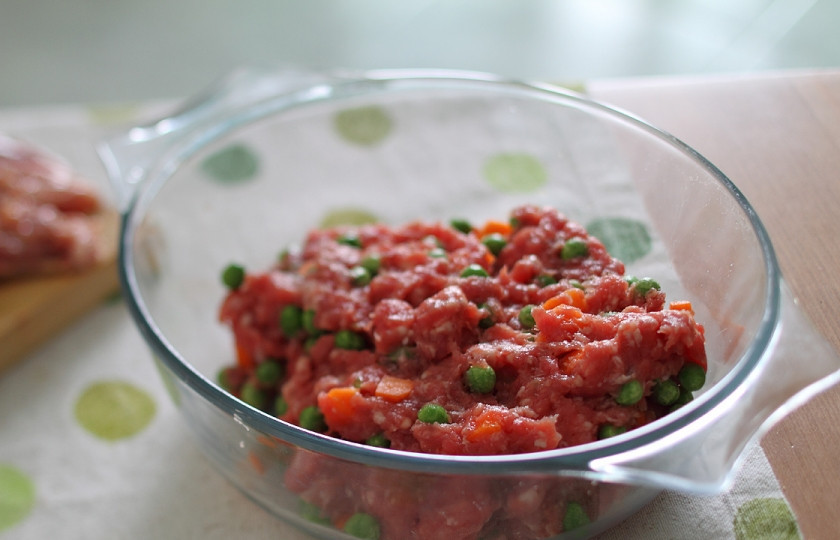 1. Этап. Галантин из курицы: Смешиваю в чашке два вида фарша, по вкусу немного солю и перчу, а затем добавляю размороженный зеленый горошек и морковку, которую нарезаю не слишком крупными кубиками.