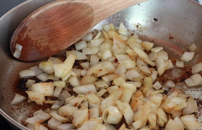 1. Этап. Вкусная говяжья подлива: 5. Нарежьте кубиками лук и измельчите чеснок. Сковороду после обжаривания мяса верните на огонь, выложите в нее лук, обжаривайте его несколько минут, затем добавьте чеснок.