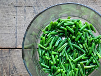 1. Этап. Слоеный салат Праздничный: 1. Бекон нарежьте и обжарьте в сковороде на среднем огне, пока он не станет хрустящим. Затем выберите из сковороды на бумажные полотенца. Зеленую фасоль промойте, обрежьте кончики, разрежьте напополам, выложите в сковороду, где жарили бекон. Добавьте полстакана воды, посолите и тушите 2-3 минуты, пока вода не выпарится. Затем выложите в большую стеклянную миску. Это - первый слой.