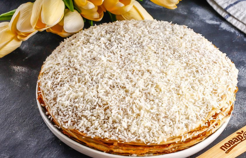 1. Этап. Кокосовый блинный торт: Таким образом соберите весь торт, присыпая стружку через каждые три блина. Верх десерта так же украсьте кокосовой стружкой. Поместите лакомство в холодильник на 1 час для пропитывания.