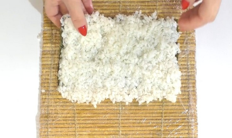 1. Этап. Роллы в духовке: Готовим роллы: на половину листа нори выложите рис и распределите его равномерным слоем.