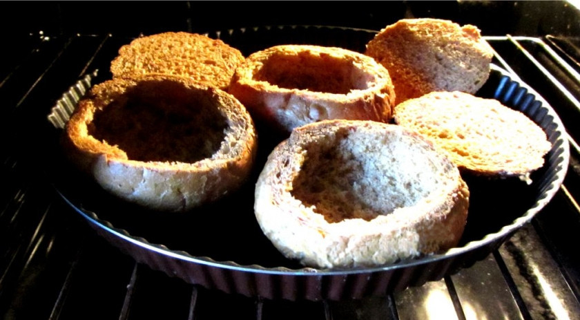 1. Этап. Чечевичный суп в хлебе: 5. Пока суп варится, подготовьте хлеб. Верхушки отрежьте, мякоть вытащите с помощью ложки и поставьте их в духовку на максимальную температуру на 5 минут, чтобы подсохли немного.