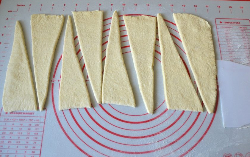 1. Этап. Круассаны с заварным кремом: Теперь перейдите к выпечке круассанов. Раскатайте тесто в прямоугольный пласт, нарежьте на треугольники.