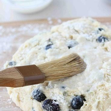 1. Этап. Лепешки с черникой: 4. Выложить тесто на слегка посыпанную мукой поверхность и замесить 5 или 6 раз. Сформировать из теста диск. С помощью кисти смазать небольшим количеством молока сверху. Вы можете этого не делать, если хотите получить менее калорийную выпечку.