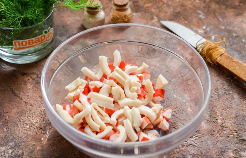 1. Этап. Салат Нептун с красной икрой: Кальмар нарежьте небольшими полосками или кубиками, добавьте к крабовым палочкам.