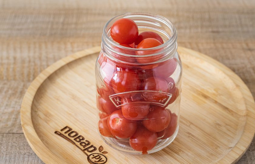 1. Этап. Помидоры с чесноком без уксуса на зиму: Выложите в тёплую стерилизованную банку помидоры.
