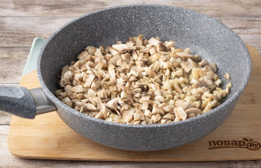 1. Этап. Картофельная запеканка с сосисками и грибами: Шампиньоны помойте, мелко порубите на кубики. Разогрейте сковороду на среднем огне и обжарьте грибы до золотистого цвета. Посолите и поперчите по вкусу в конце.