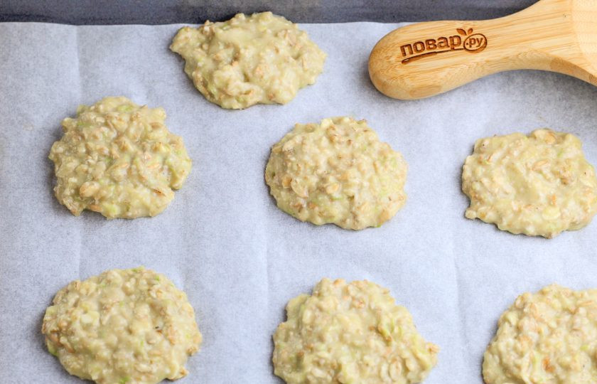 1. Этап. Печенье из кабачков с овсяными хлопьями: Застелите противень пергаментной бумагой и выложите столовой ложкой небольшие части теста на расстоянии друг от друга. Прогрейте духовку до 180 градусов.