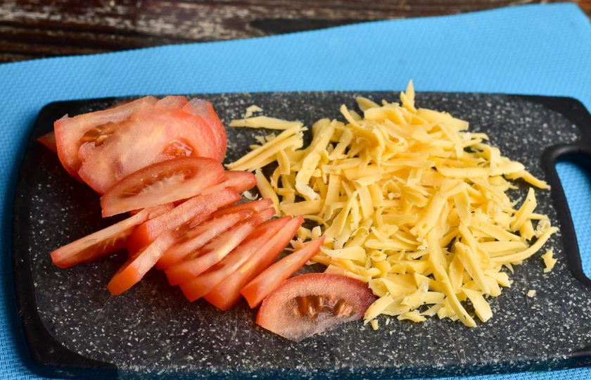 1. Этап. Заливной пирог с помидорами и сыром: Натрите твердый сыр на крупной терке. Помидор вымойте и нарежьте кусочками.