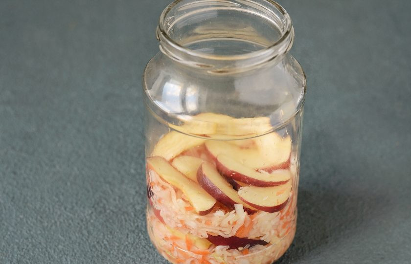 1. Этап. Квашеная капуста с клюквой и яблоками: Выложите в банку слоями капусту и яблоки.