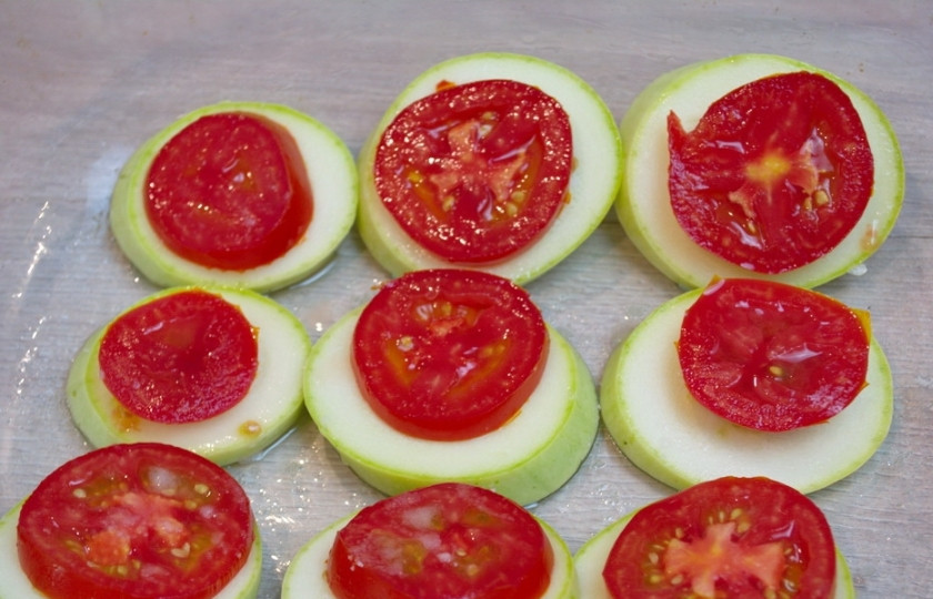 1. Этап. Кабачки с помидорами и сыром в духовке: На каждый кабачок уложите кружочек помидора. Лучше подобрать так, чтобы диаметр помидора совпадал с размером кабачка. Блюдо будет эстетичнее и красивее. Здесь тоже можно совсем немного посолить и поперчить, к примеру. Но это вовсе не обязательно.