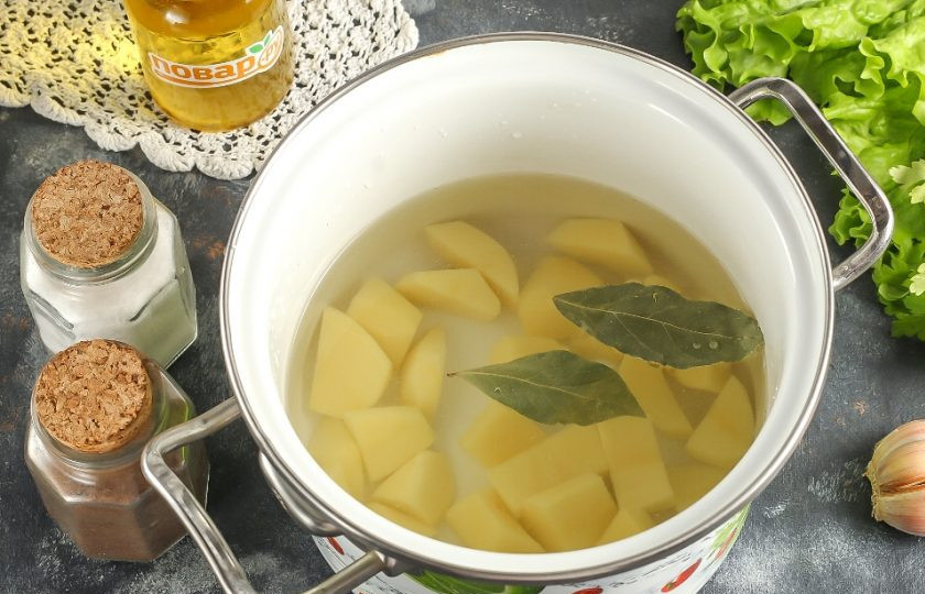 1. Этап. Сырный суп с пельменями: Картофель нарежьте средними кубиками, выложите в кастрюлю и залейте водой. Всыпьте лавровые листья и соль, поместите емкость на плиту. Отварите картофель примерно 15 минут.