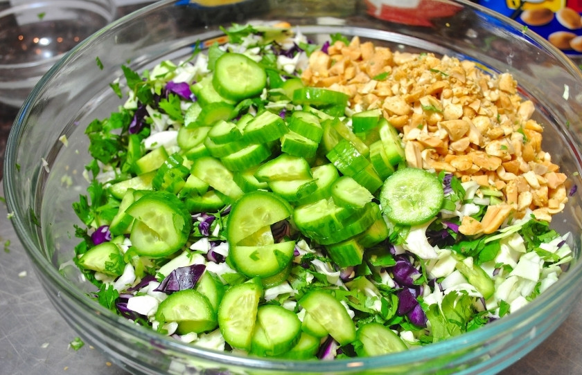 1. Этап. Салат с арахисом: Нарежьте огурцы колечками или полукольцами. Измельчите арахис, но не мелко. И перемешайте всё вместе с зеленью и капустой.