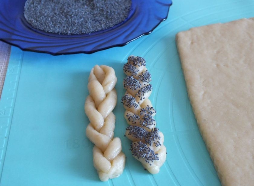 1. Этап. Печенье Косичка: Косичку разделите пополам. Смажьте взбитым яйцом и обмакните в мак. Таким же образом поступите с остальными полосками. Разогрейте духовку до 200 градусов.