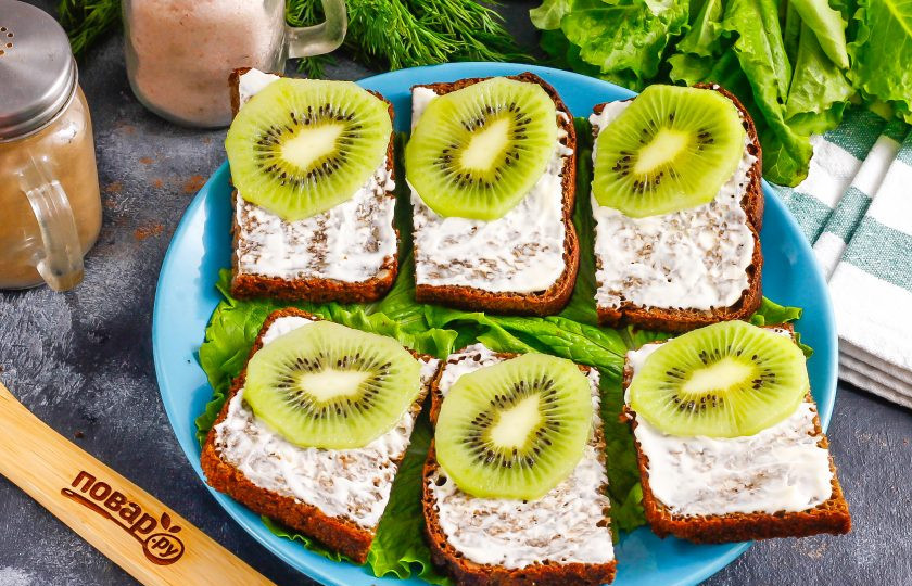 1. Этап. Бутерброды с красной рыбой и киви: Очистите киви от кожуры, промойте в воде и нарежьте тонкими слайсами. Выложите на одну часть бутерброда, оставляя вторую для красной рыбы.