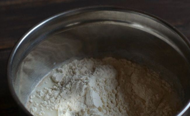 1. Этап. Оладушки на дрожжах и молоке: Затем отделите сто грамм пшеничной муки и всыпьте ее в молочную смесь с дрожжами. Тщательно перемешайте все венчиком или ложкой.