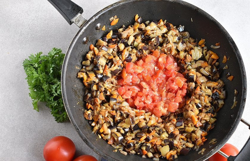 1. Этап. Икра из баклажанов на зиму: Раздвиньте овощи к краям и выложите в середину помидоры, нарезанные кубиками. Посолите и поперчите. Я всегда солю чуть сильнее, чем просто для еды. Тушите помидоры помешивая внутри посуды, пока они не начнут отделять масло. Затем перемешайте все вместе, еще немного убавьте огонь и тушите минут 10, помешивая. Не давайте пригорать.