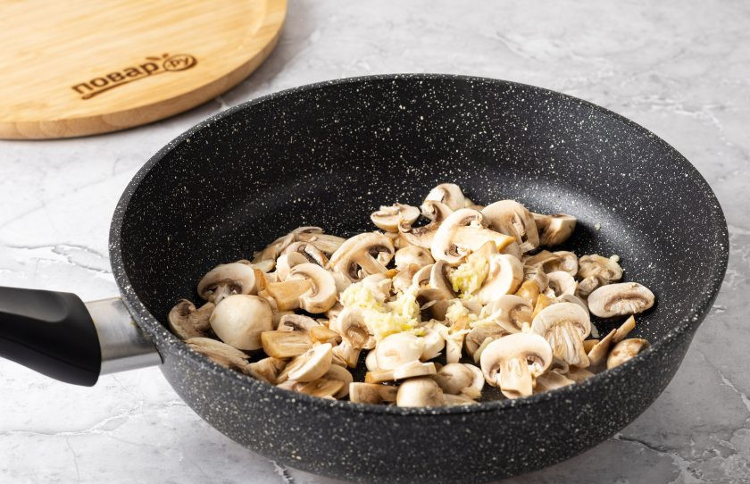 1. Этап. Брускетта с грибами и грушей: Шампиньоны помойте, обсушите и нарежьте пластинами. Чеснок пропустите через пресс. Разогрейте сковороду с растительным маслом и обжарьте грибы с чесноком на среднем огне до золотистого цвета. В конце подсолите и поперчите.