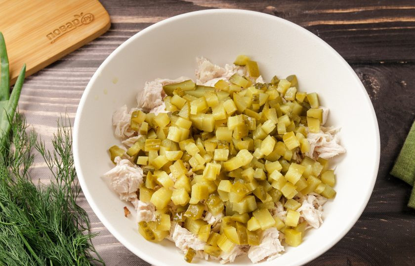 1. Этап. Салат с курицей, грибами и маринованными огурцами: Небольшими кубиками нарежьте маринованные огурцы и добавьте к грудке.