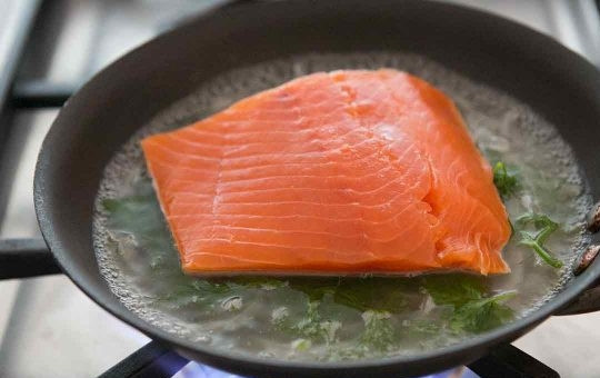 1. Этап. Лосось в вине на сковороде: 1. Промойте рыбу и вытрите ее салфетками, посолите. Почистите и нарежьте тонкими ломтиками шалот. Промойте под проточной водой зелень. Влейте вино и воду в глубокую кастрюлю, уложите на дно зелень и овощи, доведите до кипения на среднем огне.